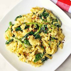 a white plate topped with scrambled eggs and spinach