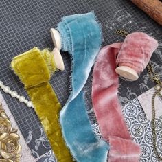 three different colored scarves sitting on top of a table next to beads and chains