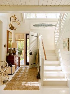 a hallway with white walls and carpeted flooring next to a staircase leading up to the second floor