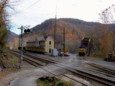 an old train station in the mountains with tracks running through it and houses on either side