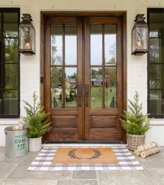 two potted plants are sitting on the front door mat in front of a house