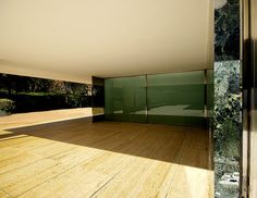 an empty room with wooden floors and glass doors on the wall, in front of trees