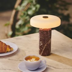 a table topped with two plates of food and a jar filled with liquid next to a cup of coffee