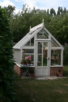 a small white greenhouse sitting on top of a lush green field