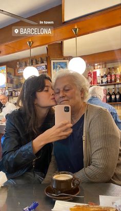 two women sitting at a table kissing each other