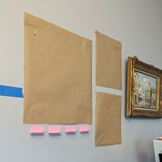 there are several pieces of paper taped to the wall next to an old framed painting