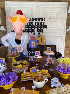 a table topped with lots of food and cupcakes next to a person wearing an animal mask