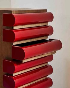 a red cabinet sitting on top of a hard wood floor next to a white wall