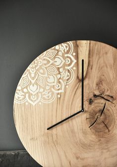 a wooden clock with an intricate design on it's face is shown in front of a gray wall