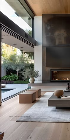 a modern living room with wood floors and large windows on the wall, along with a fireplace