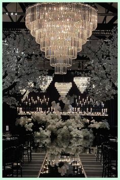 a large chandelier hanging from the ceiling above a table with flowers and candles