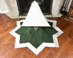 a white christmas tree sitting on top of a wooden floor next to a fire place