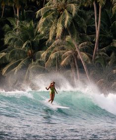 a woman riding a wave on top of a surfboard in front of palm trees