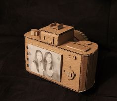 an old fashioned camera made out of cardboard with two girls on it's side