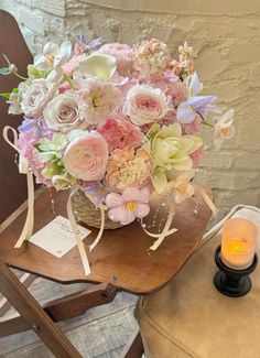 a vase filled with flowers sitting on top of a wooden chair next to a candle