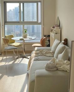 a living room filled with furniture next to a large window covered in white sheets and blankets