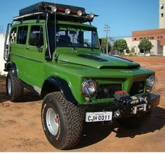 a green truck parked on top of a dirt field