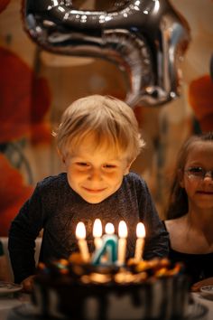 a young boy sitting in front of a birthday cake with lit candles on top of it