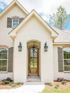 a white brick house with brown shutters on the front door and windows in the side