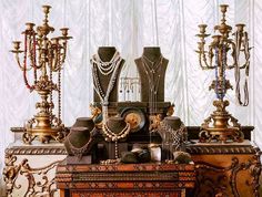 there are many different types of jewelry on the table and in front of it is a chandelier