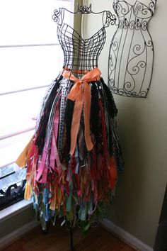 a woman's dress made out of different colored fabrics and ribbons on a mannequin