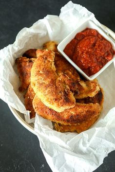 two fried food items in a basket with sauce