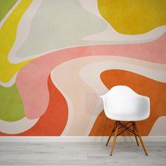 a white chair sitting in front of a wall painted with an abstract design on it