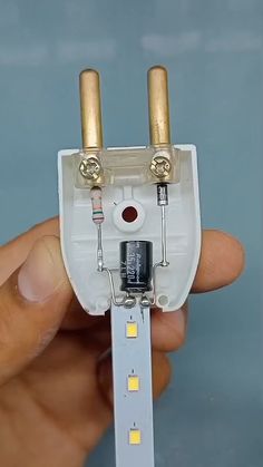 a person holding a miniature electrical device in their left hand with two lights on each side