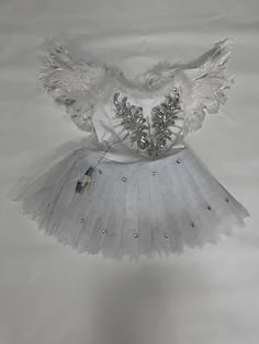 a white tutu skirt with silver sequins and wings hanging from the ceiling