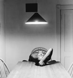 a person laying on the floor in front of a table with chairs and a lamp