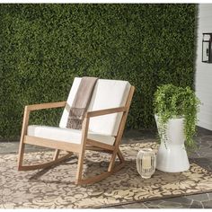 a wooden rocking chair sitting on top of a rug next to a potted plant