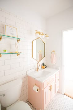 a white toilet sitting next to a pink sink in a bathroom under a large mirror