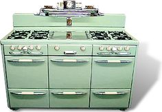 an old fashioned green stove with two ovens on it's sides and three burners