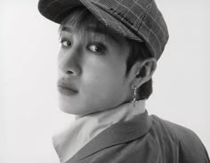 black and white photograph of a young man wearing a hat with ear studs on his ears