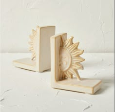 two wooden bookends with an ornate sun design on the front and back sides