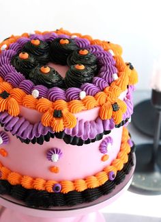 there is a cake decorated with purple and orange icing on top of a table