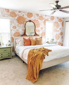 a bedroom with orange and white wallpaper and a bed in the corner, mirror on the dresser