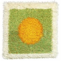 an orange is on the green and white area rug that looks like it has been made with yarn