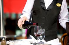 a waiter pouring wine into a glass at a restaurant