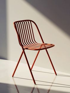 a wooden chair sitting on top of a white floor next to a wall and window