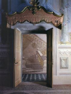 an open door leading to a stairway in a room with paintings on the walls and floor