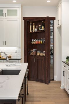 a kitchen with wooden cabinets and white counter tops, along with lots of food items on the shelves