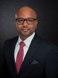 a man in a suit and red tie posing for a photo with his head turned to the side