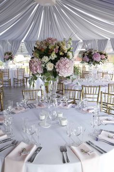 the tables are set with white linens and pink flowers in tall glass vases