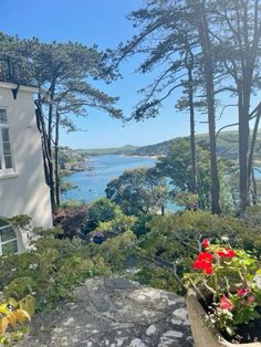 a house with flowers in front of it on the side of a hill next to water