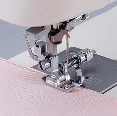 the sewing machine is working on the pink piece of material that has been sewn