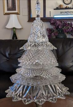 a glass christmas tree sitting on top of a table next to a black leather couch