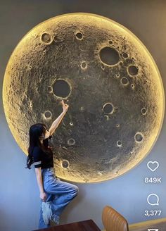 a woman standing on top of a table next to a giant moon wall hanging from the ceiling