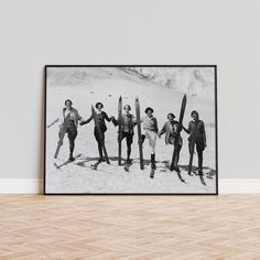 a black and white photo of four people holding surfboards in front of a wall