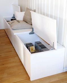 a white bed with storage underneath it in a room that has wood floors and wooden flooring